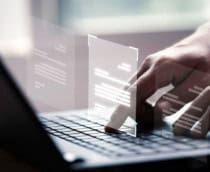 pessoa utilizando o computador com a montagem de arquivos sobre as mãos