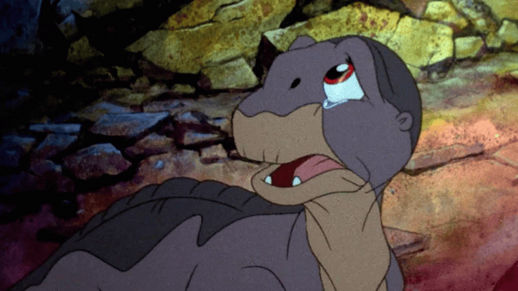Cena da animação "Em Busca do Vale Encantado" com bebê dinossauro chorando