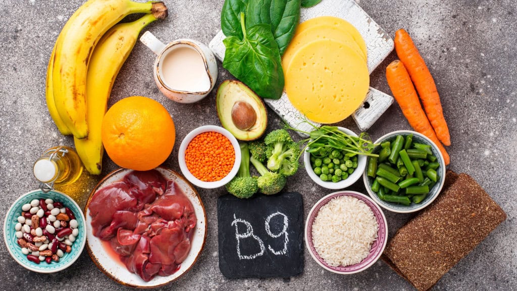 Frutais, vegetais e demais tipos de alimentos que têm vitamina B9 espalhados em cima de mesa