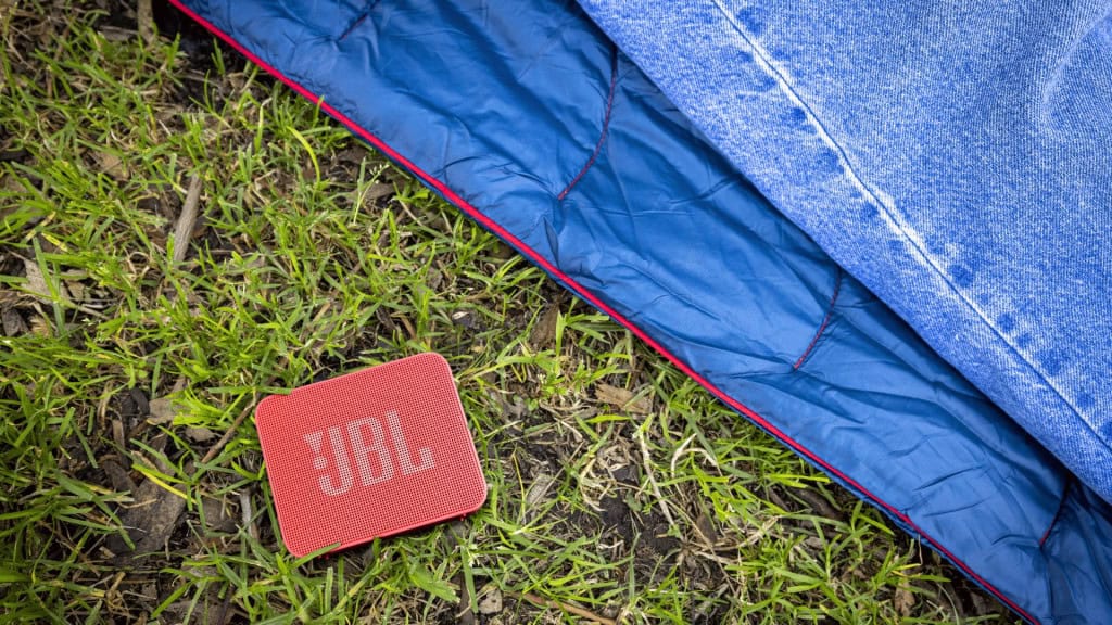 Nova caixinha JBL Go Essential 2 na grama ao lado de barraca