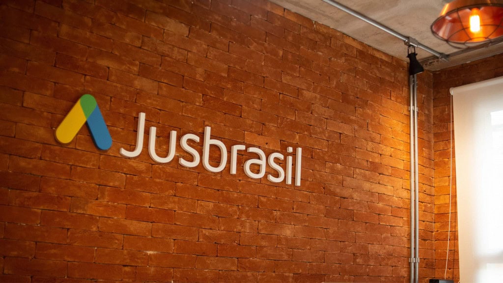 Parede de escritório com estilo tijolinhos e letreiro do Jusbrasil colado