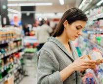 Mulher lendo ingredientes e data de validade em produto lácteo no mercado