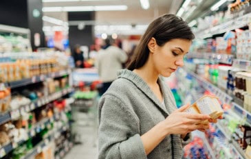 Mulher lendo ingredientes e data de validade em produto lácteo no mercado