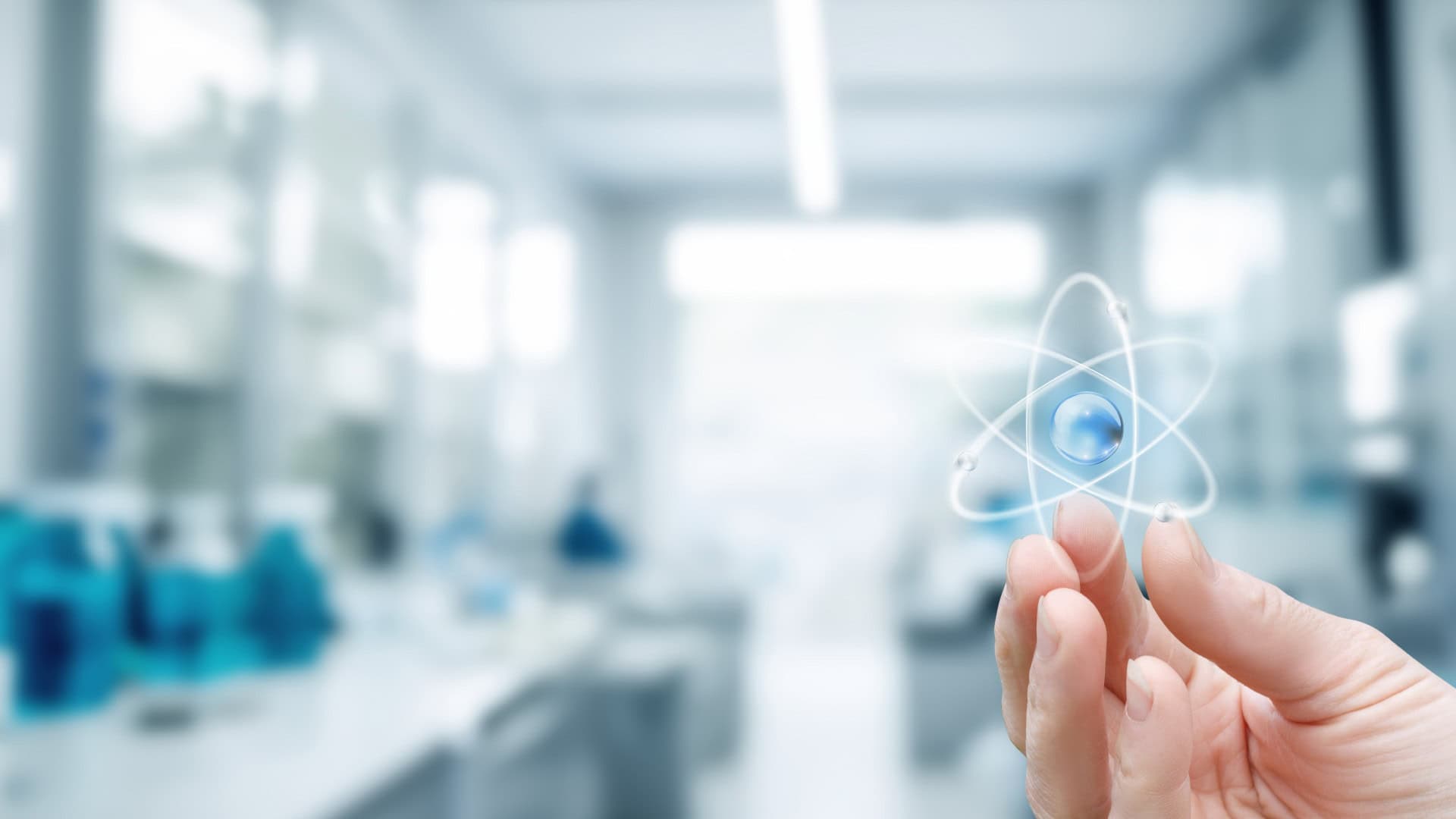 Mão segurando um holograma de um átomo, representado a energia nuclear, presente na química e física