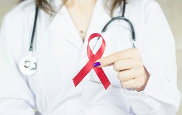 médica segurando um laço vermelho que é o simbolo da luta contra a aids