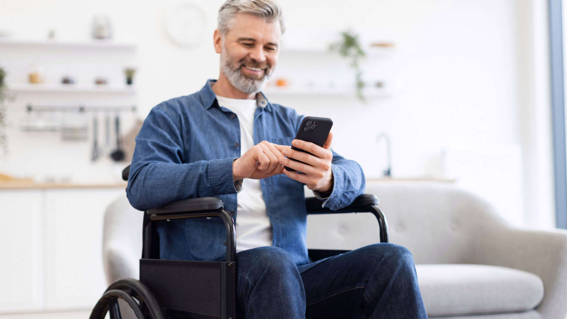 Homem sentado em cadeira de rodas usando smartphone