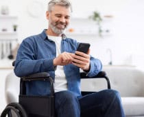 Homem sentado em cadeira de rodas usando smartphone