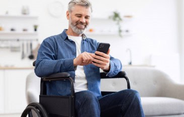 Homem sentado em cadeira de rodas usando smartphone