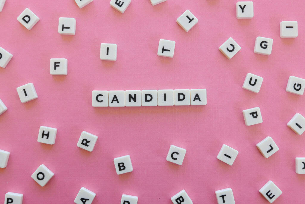 Imagem ilustrativa de tabuleiro de letras formando a palavra candida em fundo rosa
