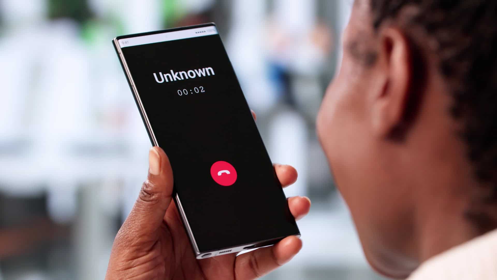 Pessoa segurando smartphone que acusa uma chamada de um número desconhecido