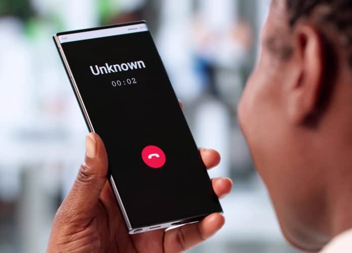 Pessoa segurando smartphone que acusa uma chamada de um número desconhecido