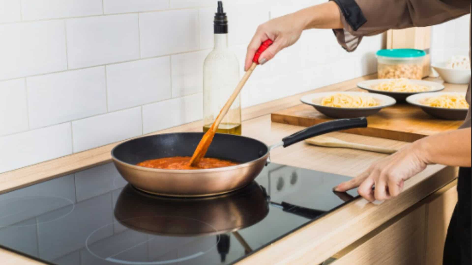 mulher cozinhando com uma frigideira em cima de um fogão de indução