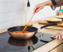mulher cozinhando com uma frigideira em cima de um fogão de indução
