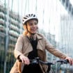 mulher de capacete com uma bicicleta no meio da cidade