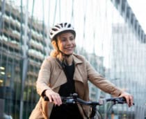 mulher de capacete com uma bicicleta no meio da cidade