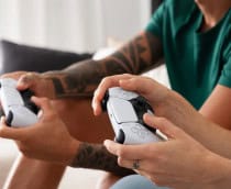 duas pessoas jogando videogame com controles do Playstation 5