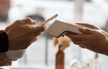 pessoa fazendo pagamento em máquina de cartão com o celular, por aproximação