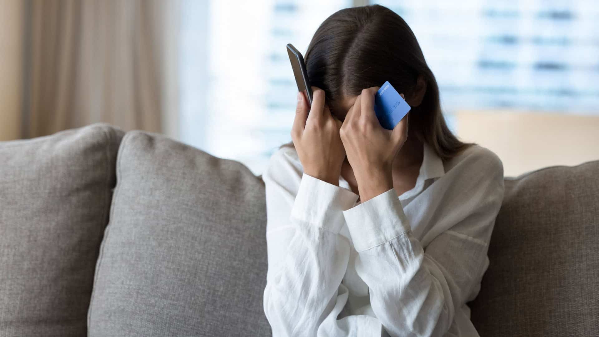 Mulher desesperada ao telefone ao sofrer um golpe
