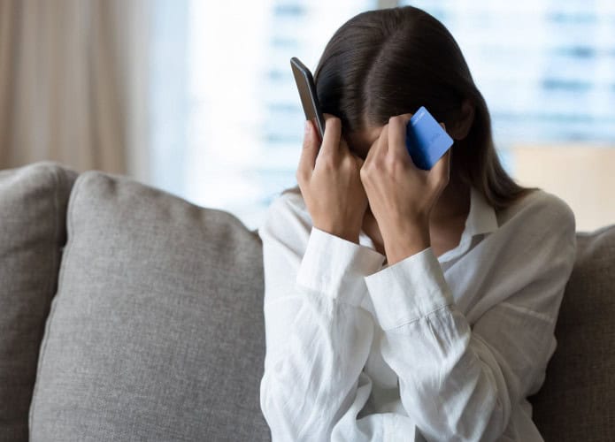 Mulher desesperada ao telefone ao sofrer um golpe