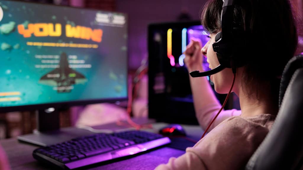Gamer comemorando vitória em jogo online de naves, animada em apartamento com luzes RGB /
