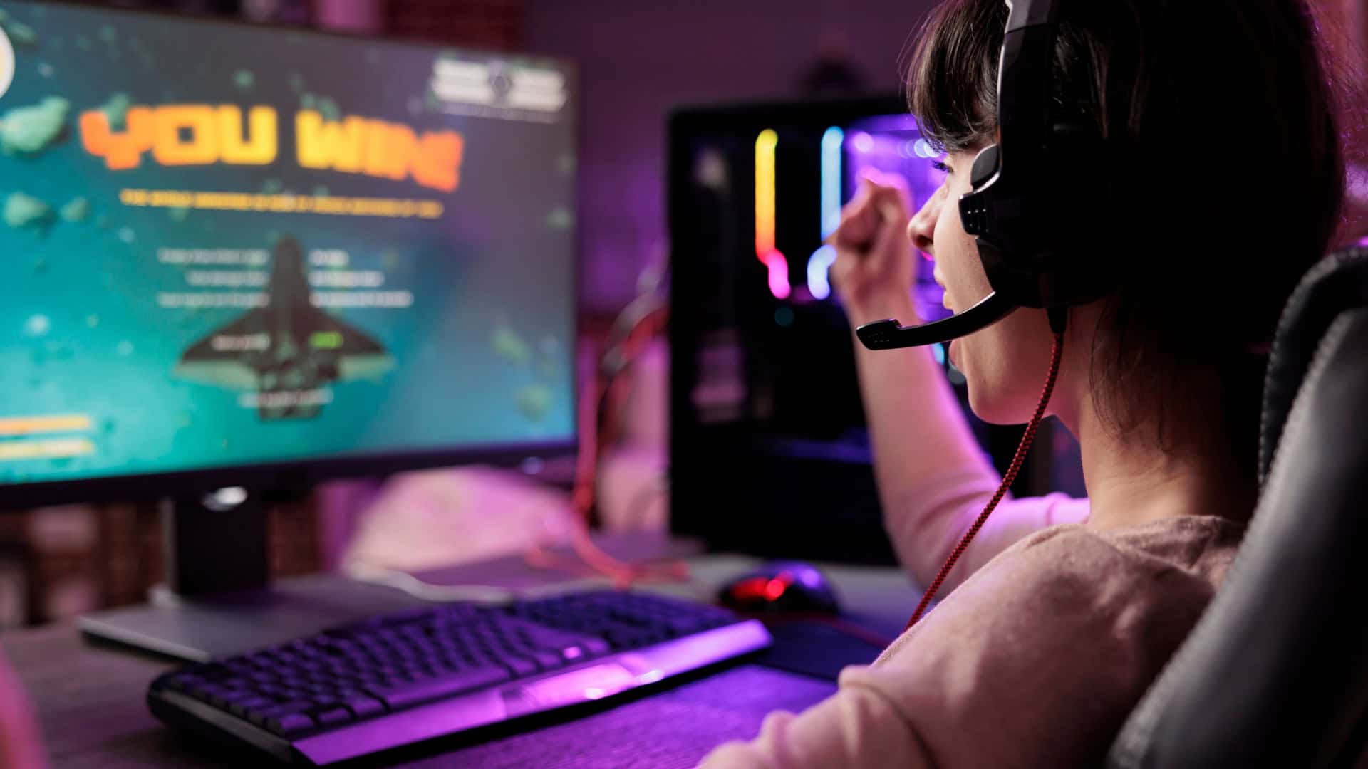 Gamer comemorando vitória em jogo online de naves, animada em apartamento com luzes RGB /