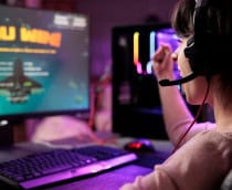 Gamer comemorando vitória em jogo online de naves, animada em apartamento com luzes RGB /