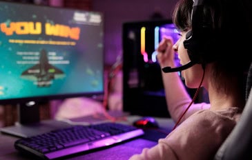 Gamer comemorando vitória em jogo online de naves, animada em apartamento com luzes RGB /