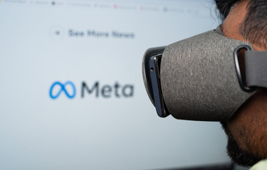 Ao fundo, desfocado, logo da Meta contrastando com o rosto de uma pessoa quase de perfil e com um óculos e realidade virtual