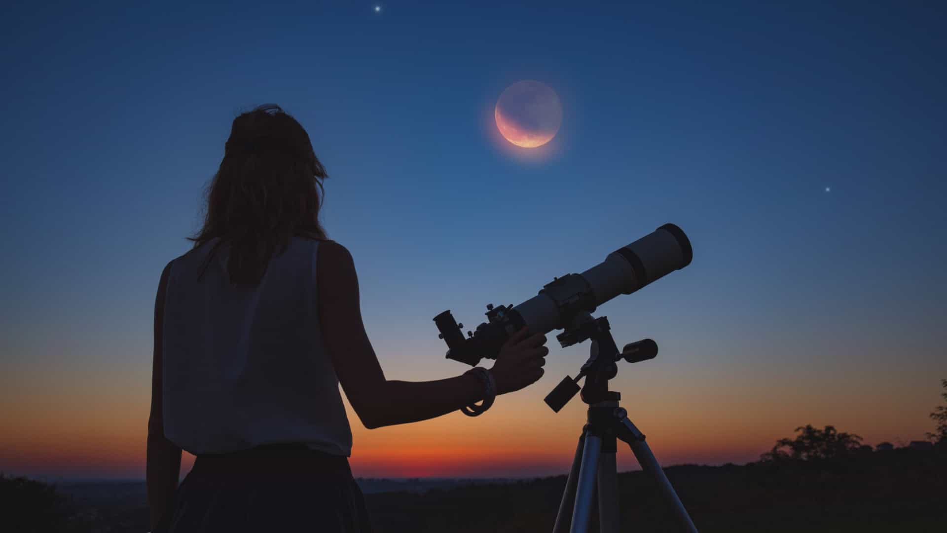 Mulher observa o céu e a Lua com um telescópio