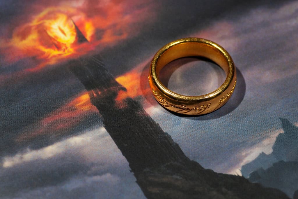 O Grande Olho de Sauron impresso em uma folha de papel, ao lado de um anel similar ao da saga "O Senhor dos Anéis"