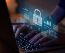 Pessoa digitando no teclado de um notebook com um cadeado holográfico pairando em cima