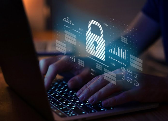 Pessoa digitando no teclado de um notebook com um cadeado holográfico pairando em cima