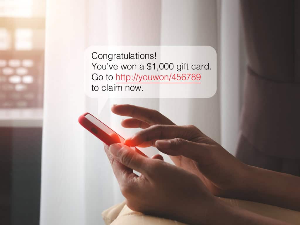 Pop-up de uma mensagem SMS pairando sobre um smartphone que está sendo utilizado por uma pessoa