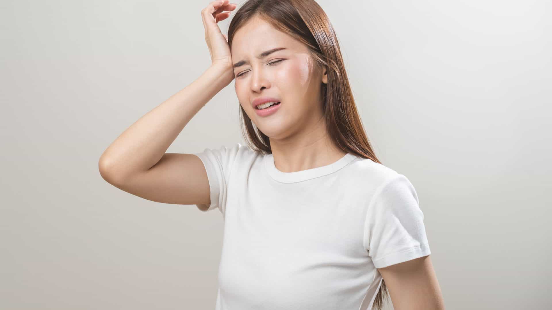 Jovem asiática com dor de cabeça ou enxaqueca, sofrendo de vertigem