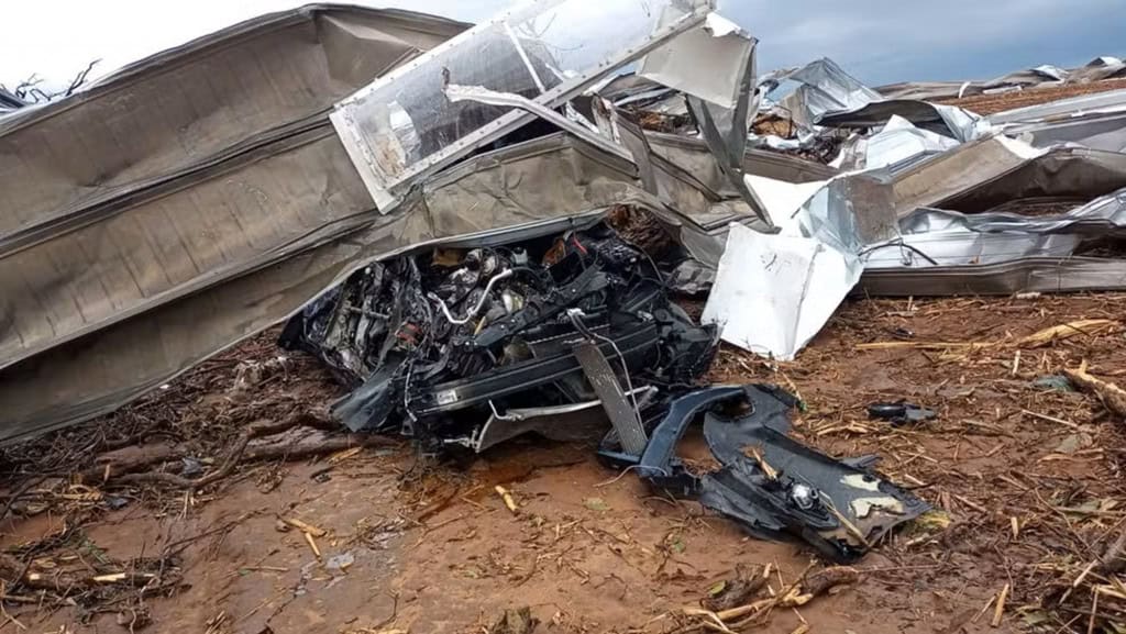 Carro destruído com partes do telhado da fábrica por cima