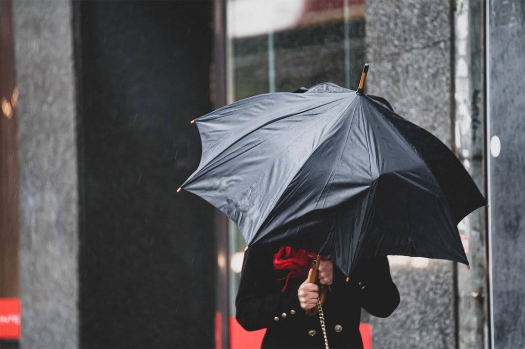 Pessoa com guarda-chuva enfrentando vento forte
