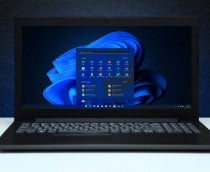 Imagem mostra área de trabalho do Windows 11 com logotipo na tela de um laptop em uma parede texturizada preta com luz azul.