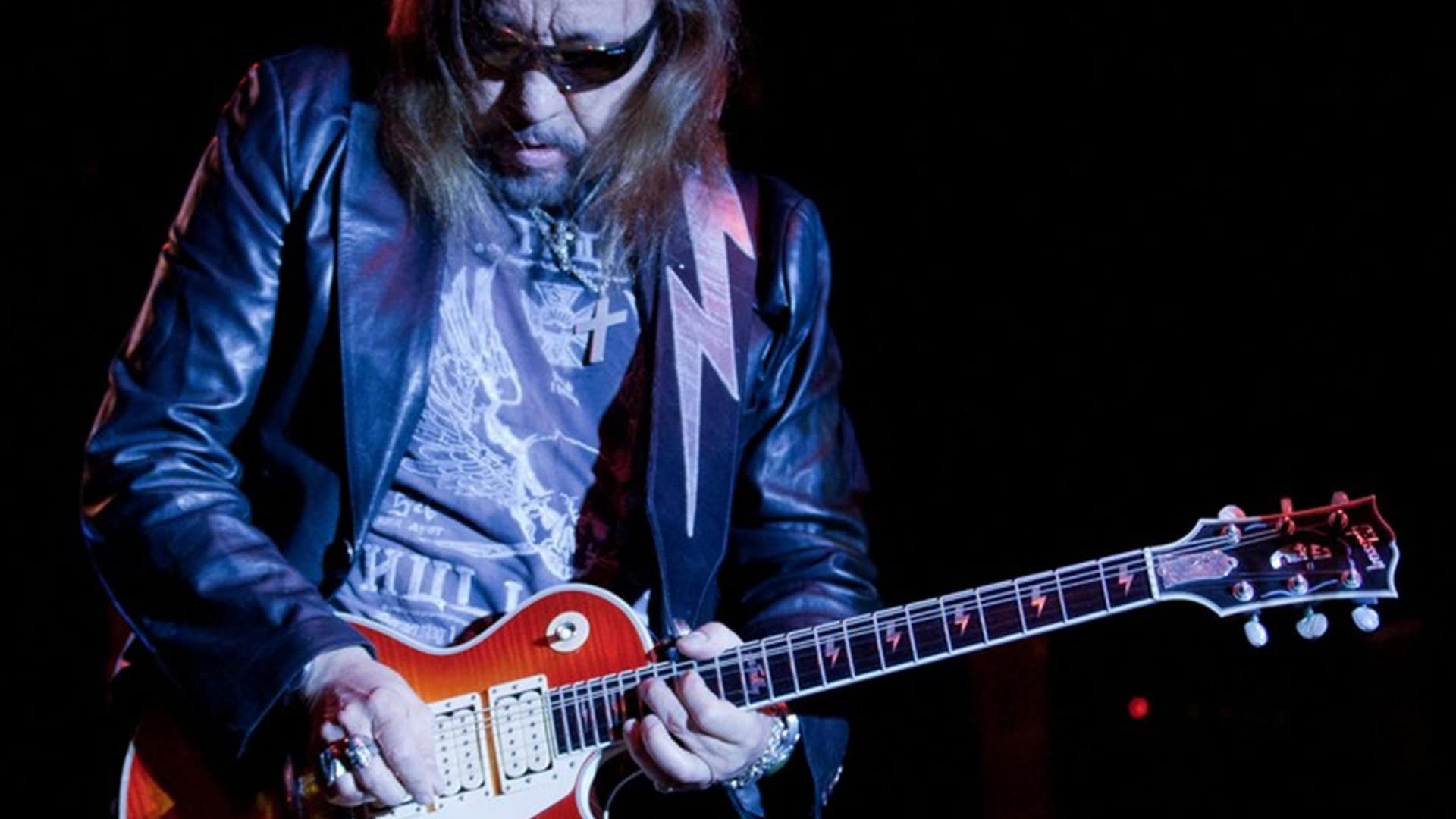 Ace Frehley tocando guitarra e usando óculos escuros