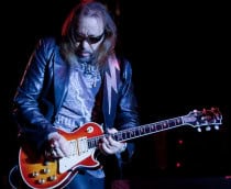 Ace Frehley tocando guitarra e usando óculos escuros