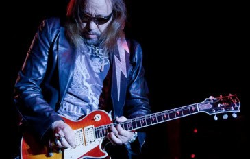 Ace Frehley tocando guitarra e usando óculos escuros