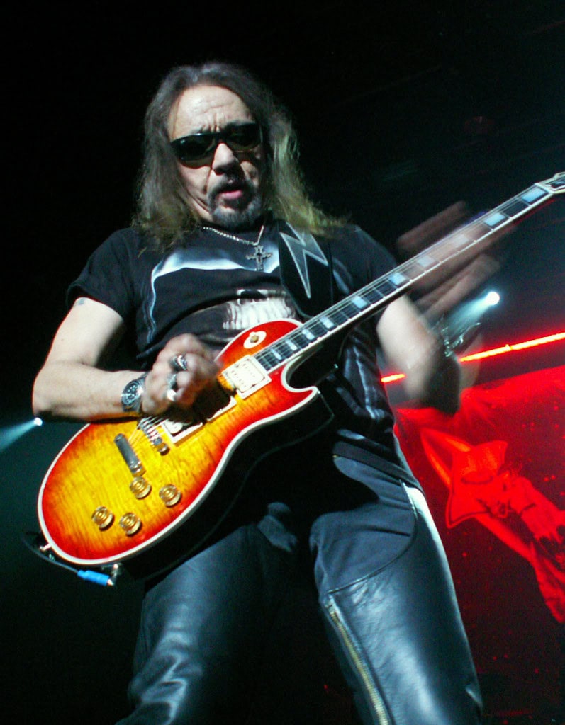 Ace Frehley tocando guitarra usando óculos escuros