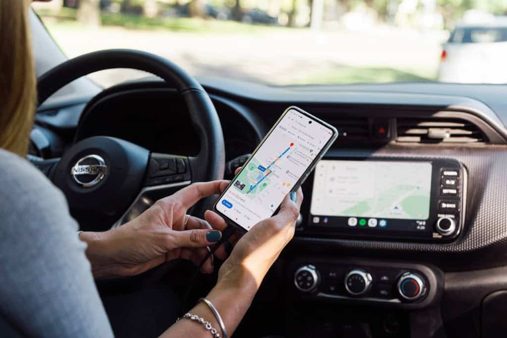 Mulher conecta Android Auto pelo celular via cabo para acessar aplicativo de navegação Google Maps