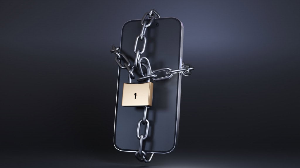 celular sobre fundo preto acorrentado e com cadeado