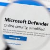 Tela de computador mostra o site do Microsoft Defender com uma lupa destacando o texto “Segurança online simplificada” e botão “Download APP”.