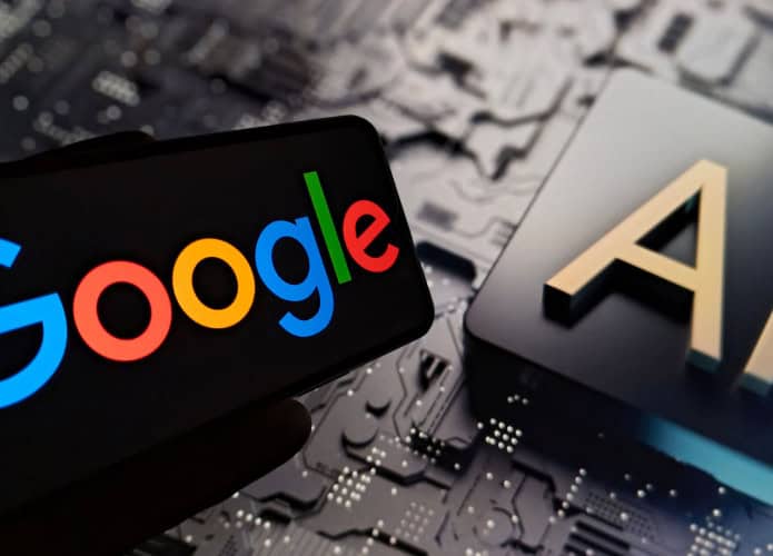 Celular com logotipo do Google na tela colocado na frente de tela exibindo ilustração de chip de inteligência artificial (IA)