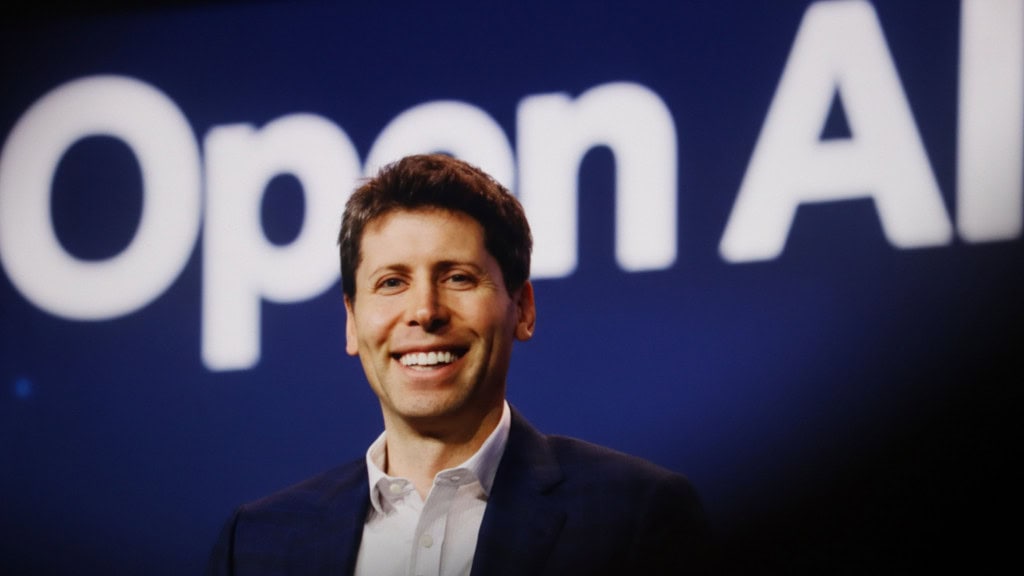Sam Altman sorrindo em frente letreiro onde está escrito OpenAI