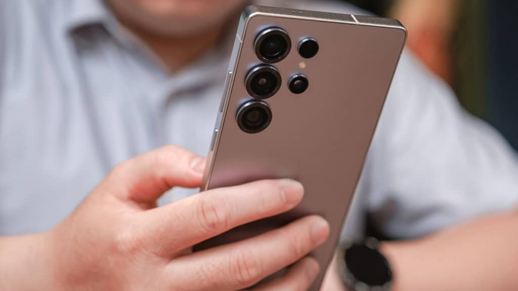 Homem segurando um Galaxy S25 Ultra, da Samsung; foto mostra a parte traseira do celular