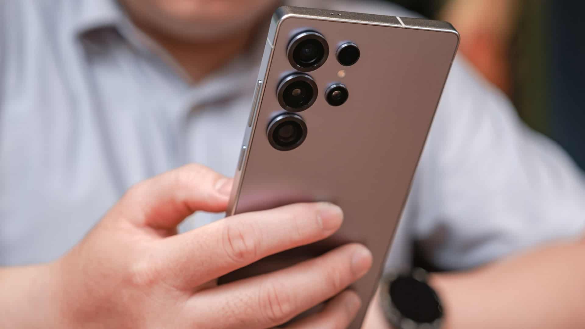 Homem segurando um Galaxy S25 Ultra, da Samsung; foto mostra a parte traseira do celular
