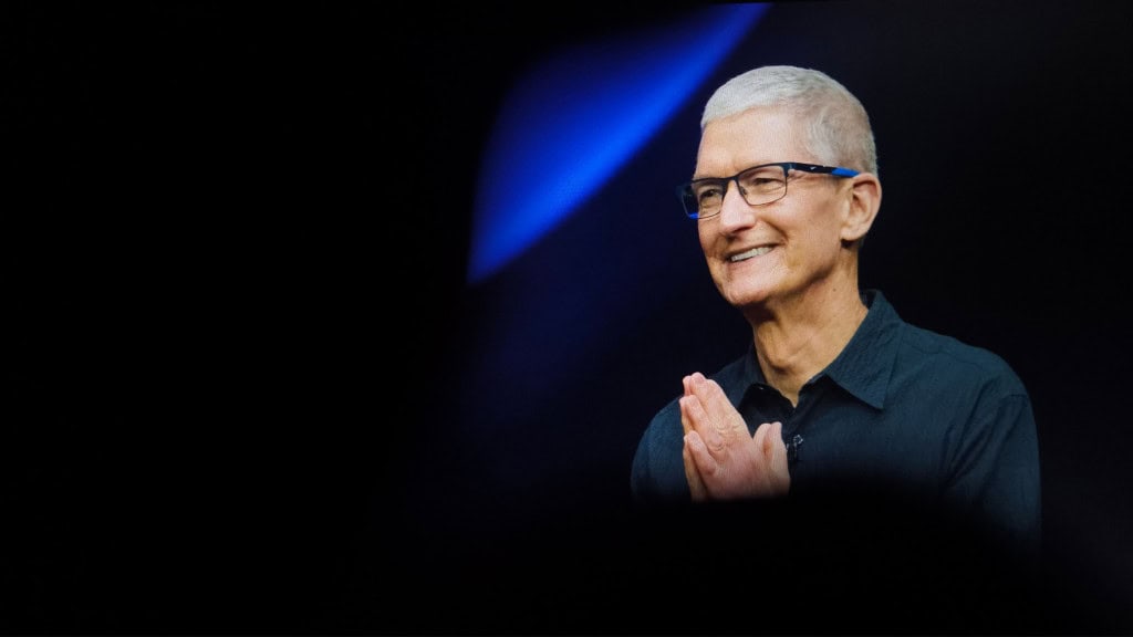 CEO da Apple, Tim Cook, olhando para o lado e sorrindo, com mãos juntas em gesto de gratidão
