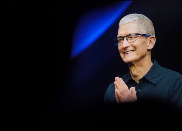 CEO da Apple, Tim Cook, olhando para o lado e sorrindo, com mãos juntas em gesto de gratidão